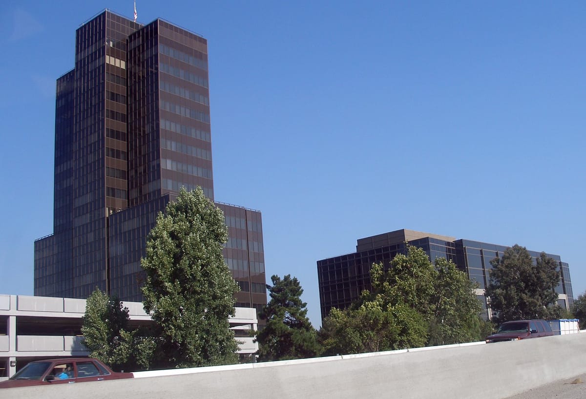 The dark glass Pruneyard towers above the trees